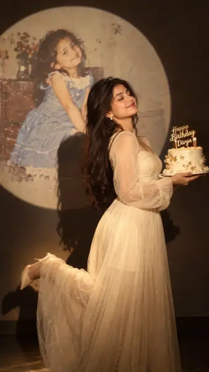 Birthday Memory Photoshoot AI Photo Prompt showing a person holding a white-and-gold birthday cake beneath a spotlight, with a vintage childhood photo projected on the wall.