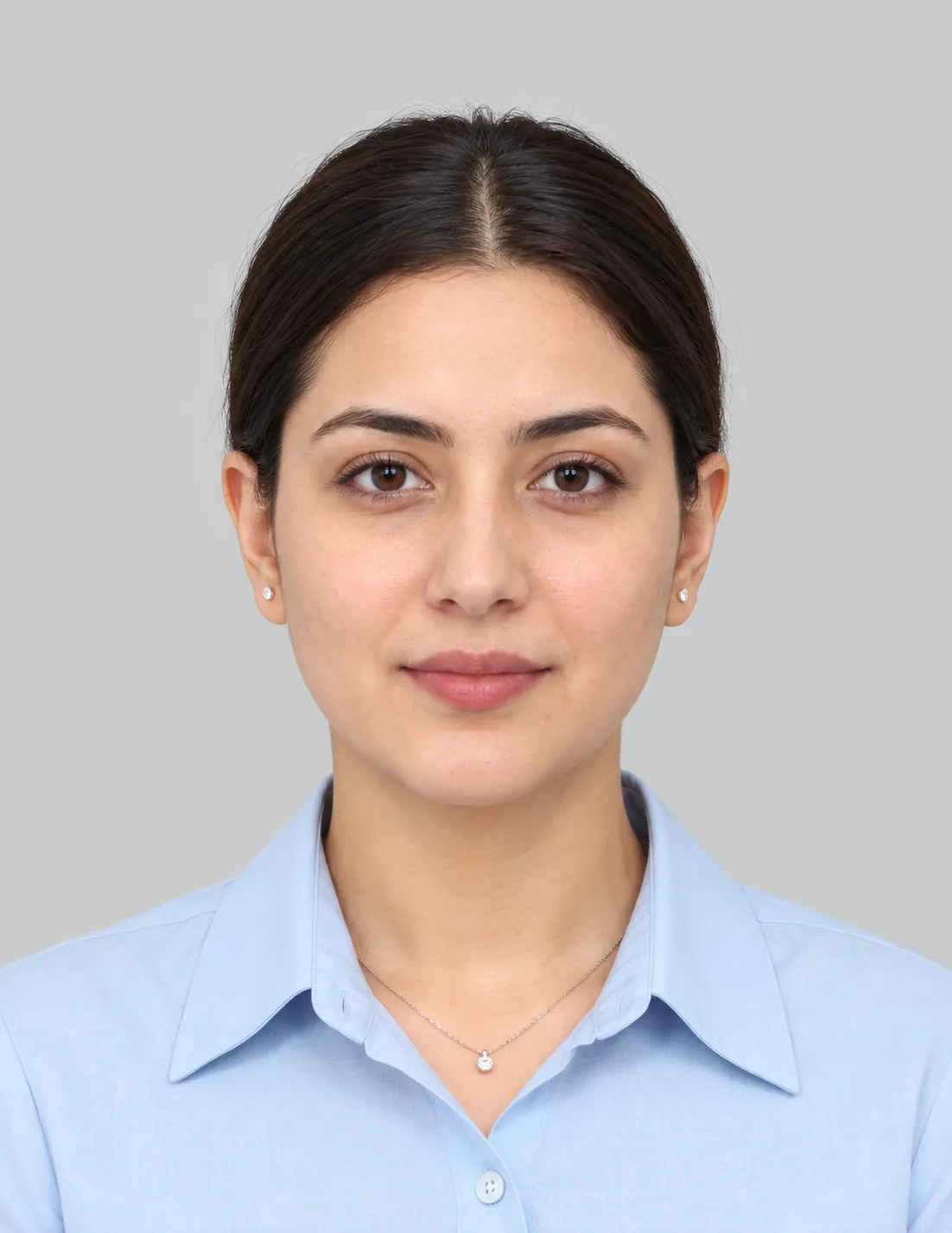 Passport Style Portrait AI Photo Prompt showing a woman with neatly styled dark hair, a light-blue collared shirt, and a neutral expression against a plain light-gray background.